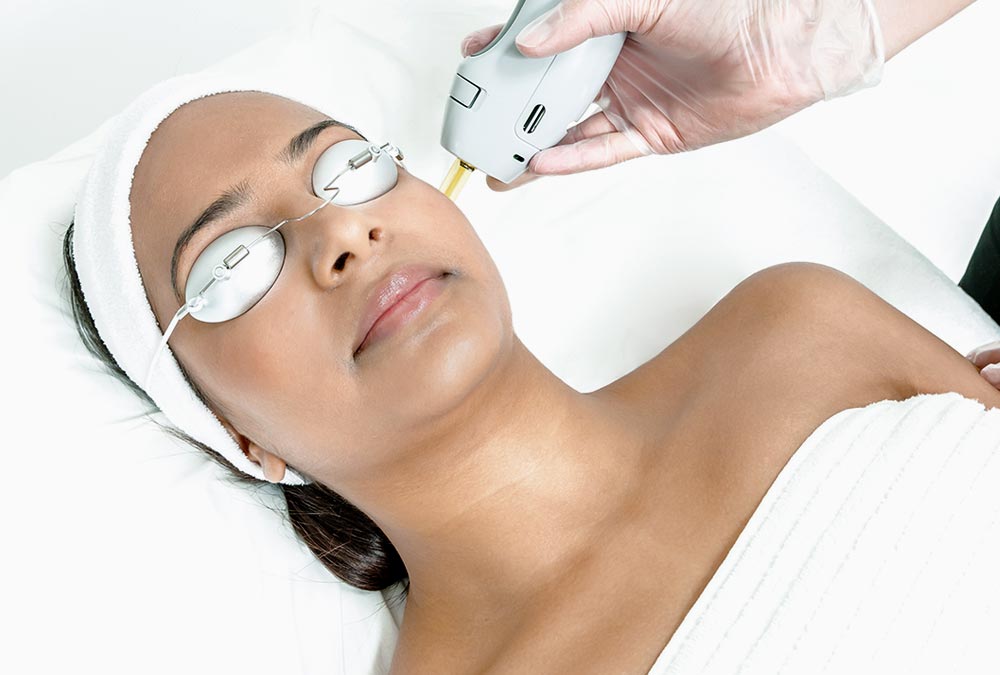 A woman receiving laser treatment on her face.